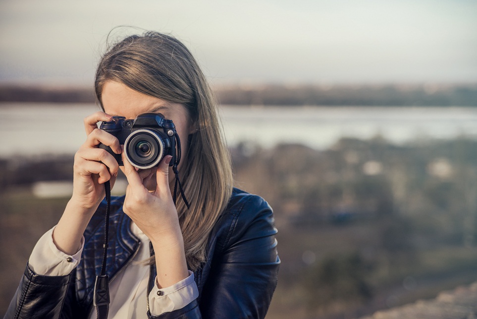 Portrait of a photographer covering her face with the camera. Ph